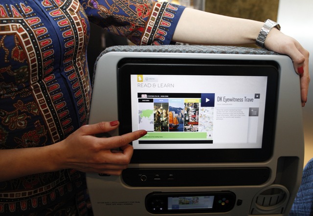 A Singapore Airlines Ltd stewardess poses with a new wider 11.1 inch monitor of the economy cabin during the launch of their new generation of cabin products at Changi Airport in Singapore July 9, 2013. The new seats and in-flight entertainment system, an investment of nearly $150 million by the company, will be rolled out from September, starting with flights between Singapore and London on eight Boeing 777-300ER aircrafts. REUTERS/Edgar Su (SINGAPORE - Tags: TRANSPORT BUSINESS) - RTX11HBH