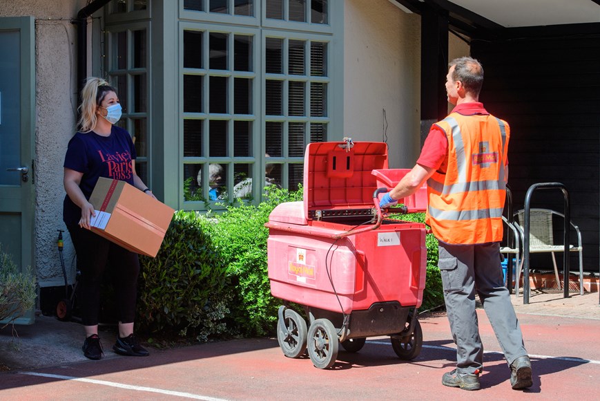 Sadie Holodynsky, a nurse from Church Farm Nursing Home, collects the parcel of personal protective equipment (PPE) as postman Simon Holmes maintains a 2 meter safe distance.  Royal Mail postman Simon Holmes delivers personal protective equipment (PPE) to Church Farm Nursing Home in Cotgrave, Nottinghamshire, during the coronavirus pandemic.  Date: May 6, 2020